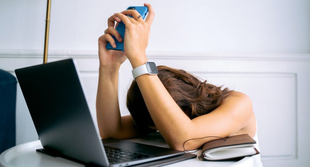 Women holding a cellphone in front of laptop