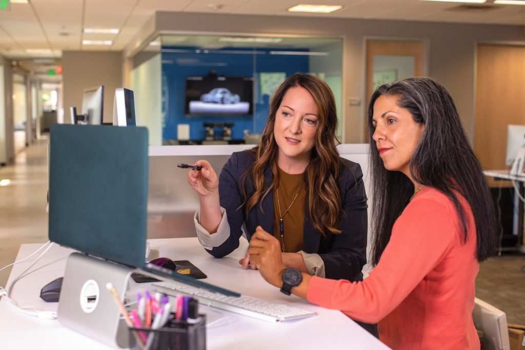 Two women discussing legal terms shown in laptop