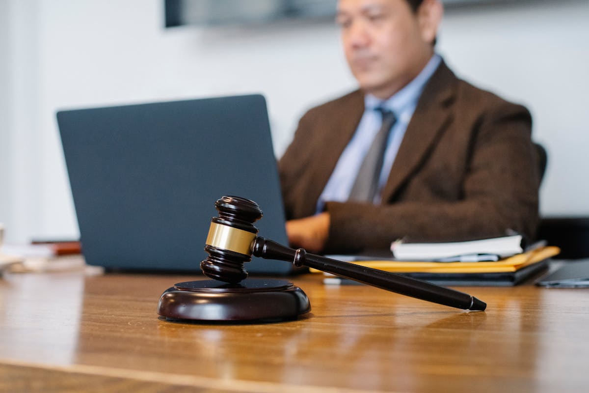 Lawyer using a laptop to locate someone and serve them legal documents, with a gavel on the desk.