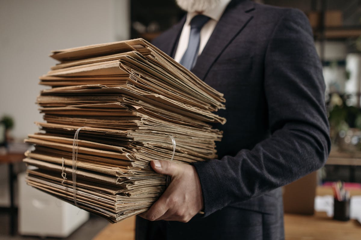 Man in a suit carrying a large stack of legal documents to get papers served to someone